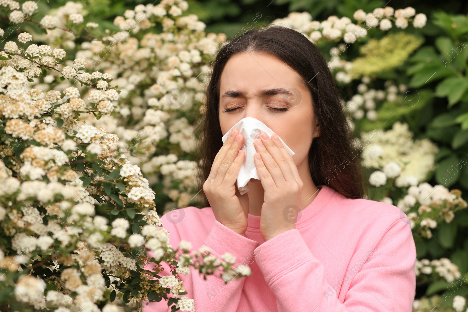 Photo of Woman suffering from seasonal pollen allergy near blossoming tree on spring day