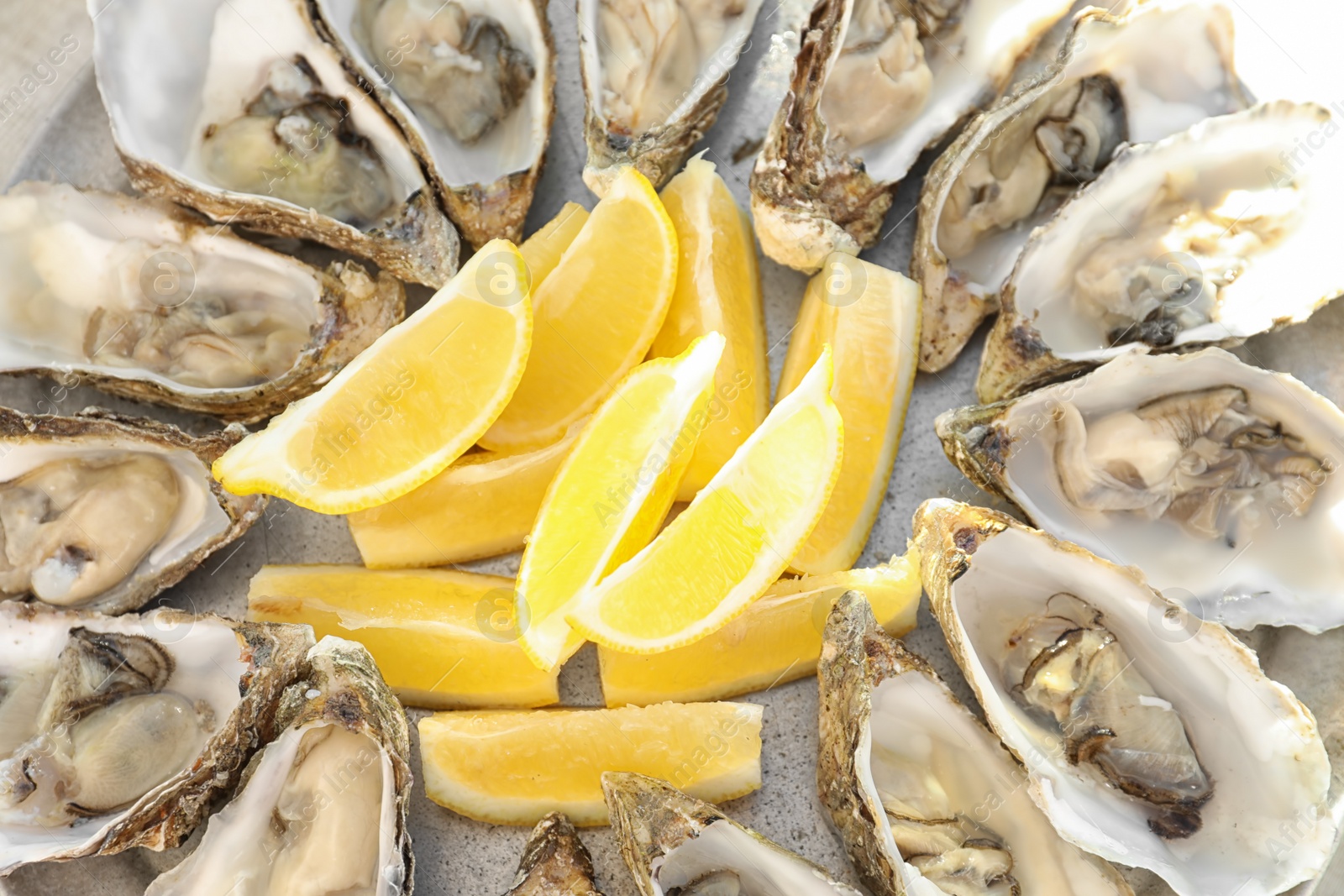 Photo of Fresh oysters with cut juicy lemon on plate, closeup