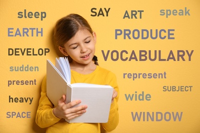 Image of Cute little girl reading vocabulary surrounded by different words in English on yellow background