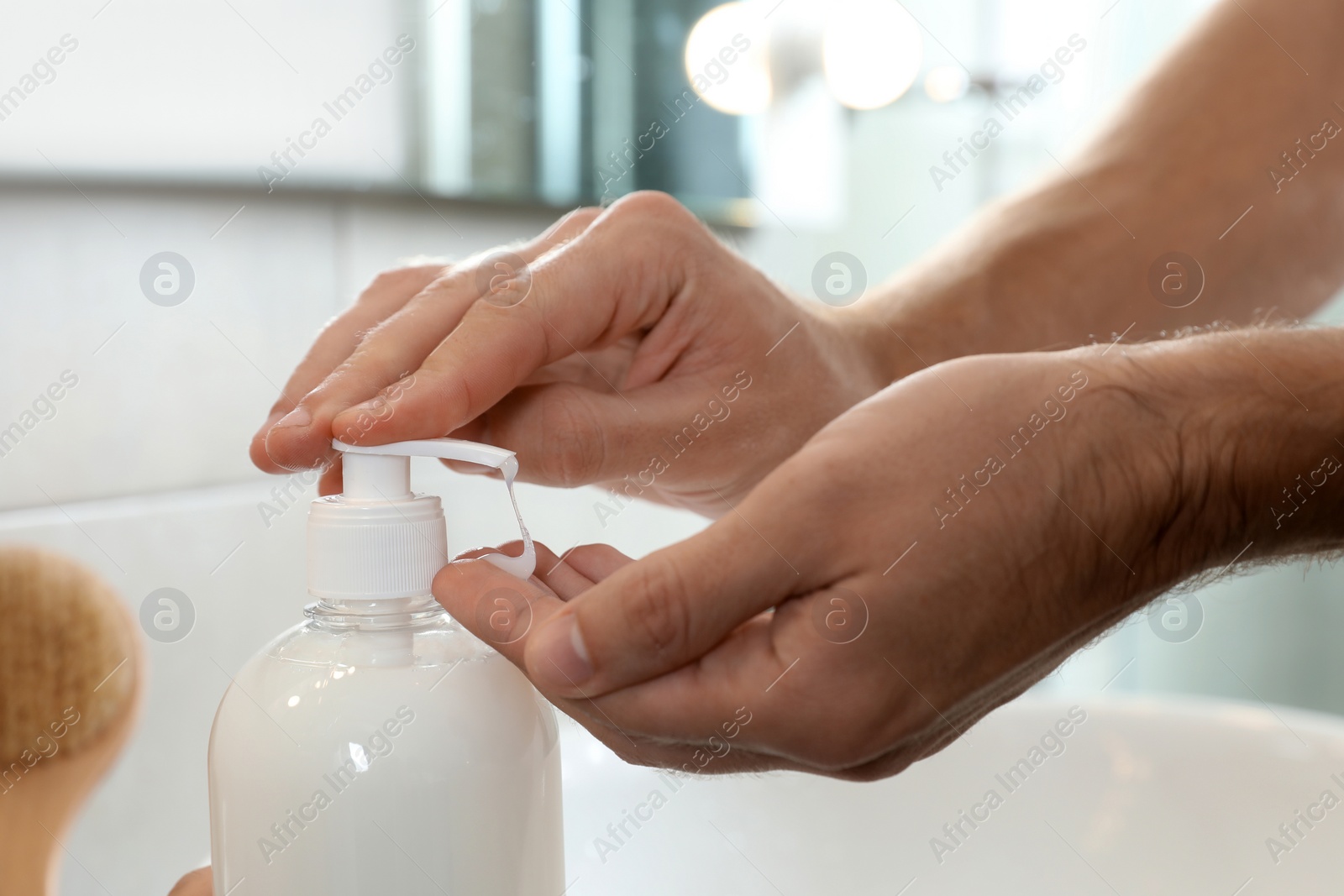 Photo of Man applying liquid soap on hand in bathroom, closeup