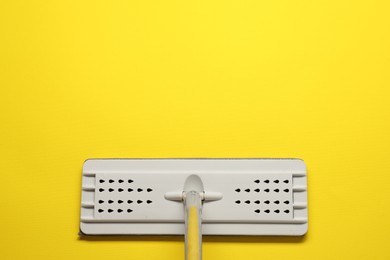 Photo of Mop with metal handle on yellow background, top view. Space for text