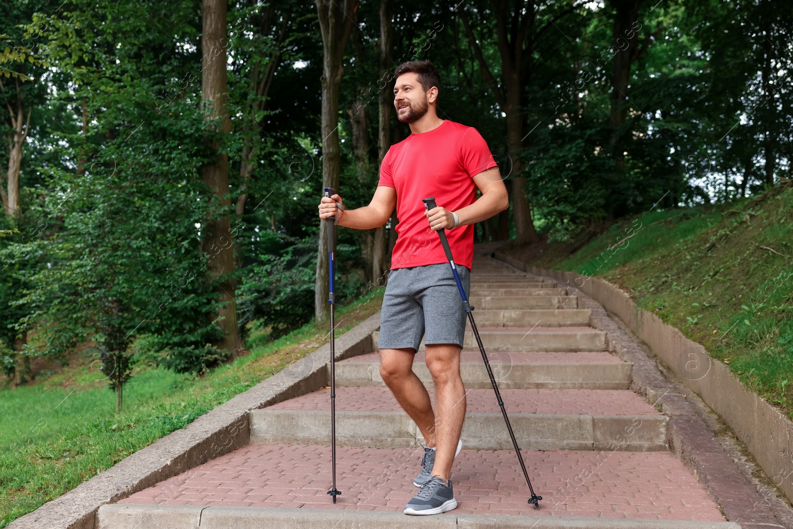 Photo of Man practicing Nordic walking with poles on steps outdoors, low angle view