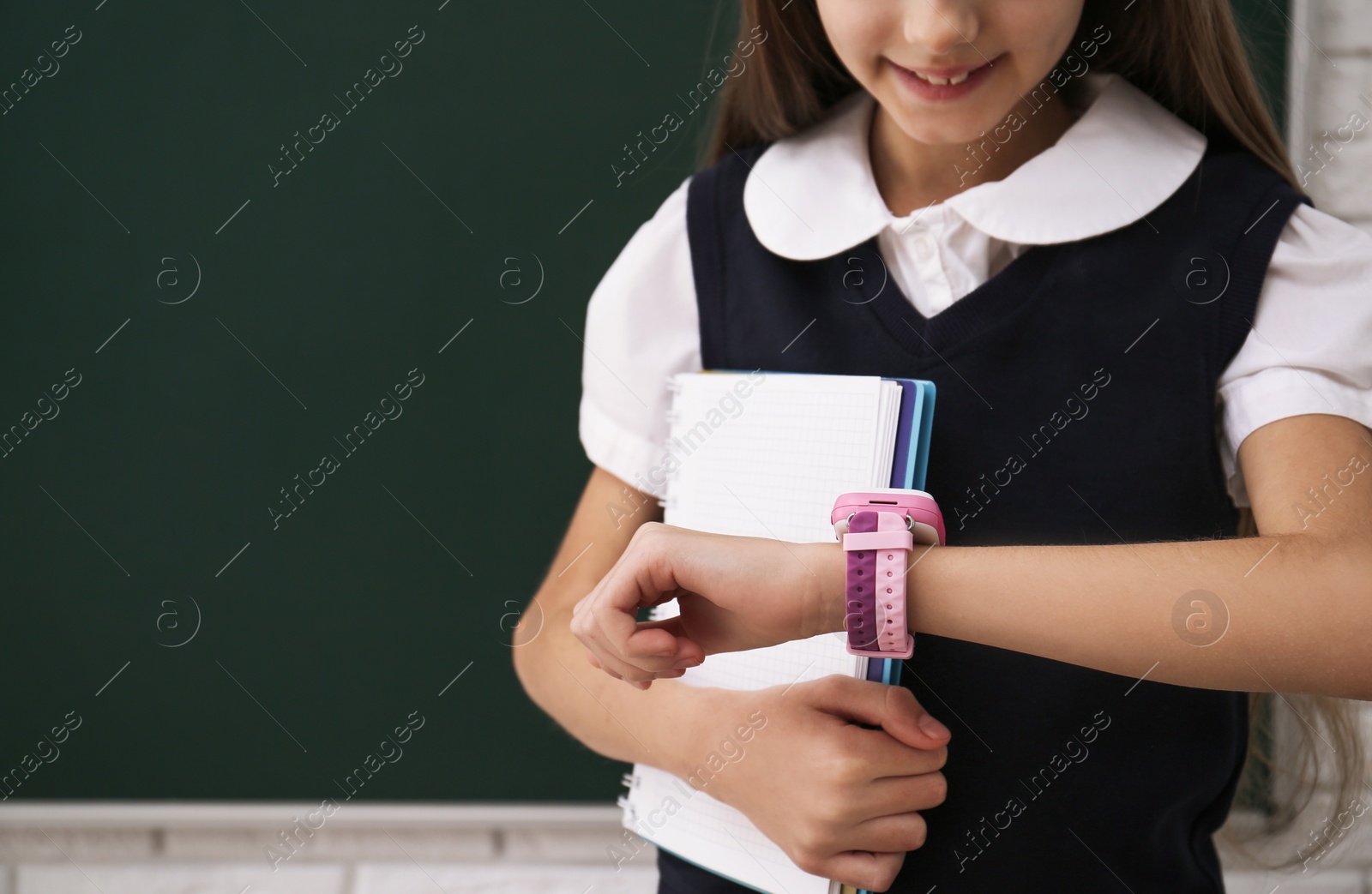 Photo of Girl with stylish smart watch in classroom, closeup