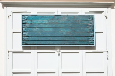 Photo of Blank advertising board on white shutters outdoors. Space for design