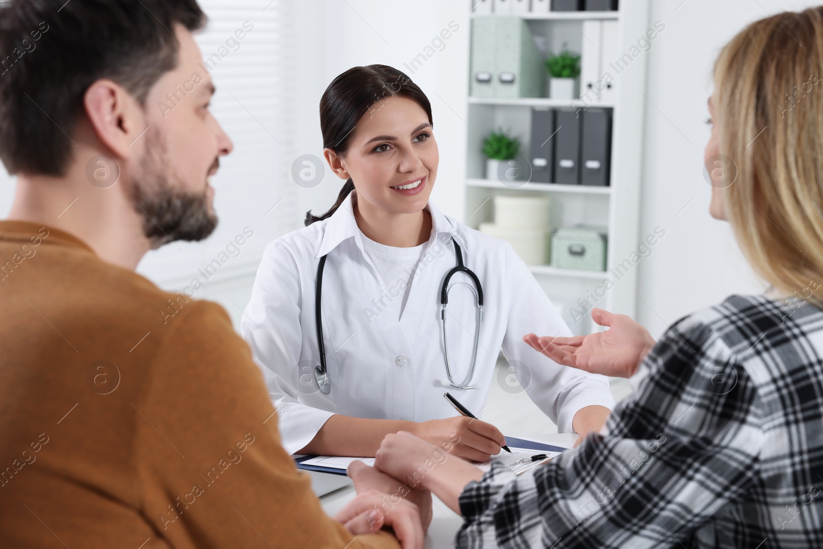 Photo of Couple having appointment with fertility doctor in clinic. Patient consultation