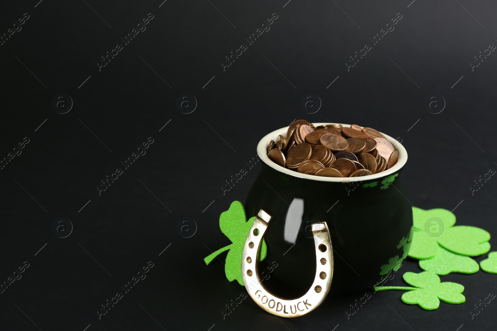 Photo of Pot of gold coins, horseshoe and clover leaves on black background, space for text. St. Patrick's Day celebration