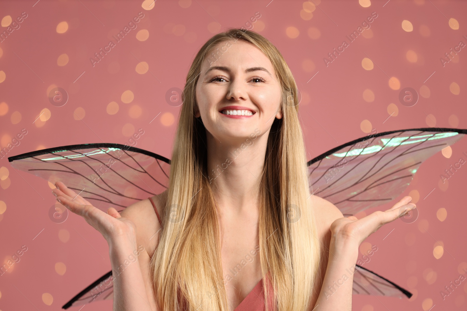 Photo of Beautiful girl in fairy costume with wings on pink background