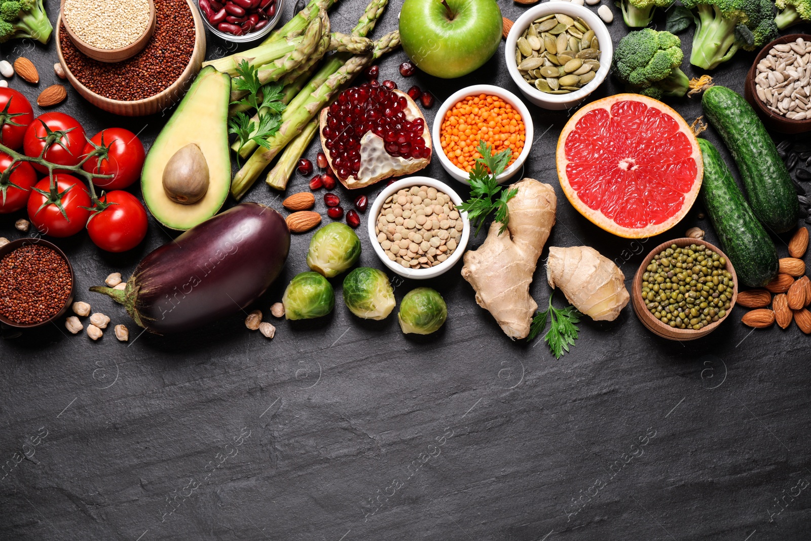 Photo of Fresh vegetables, fruits and seeds on black table, flat lay