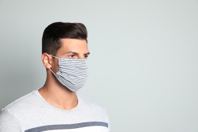 Man in protective face mask on light grey background. Space for text
