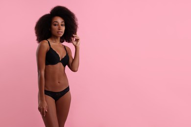 Photo of Beautiful woman in elegant black underwear on pink background, space for text