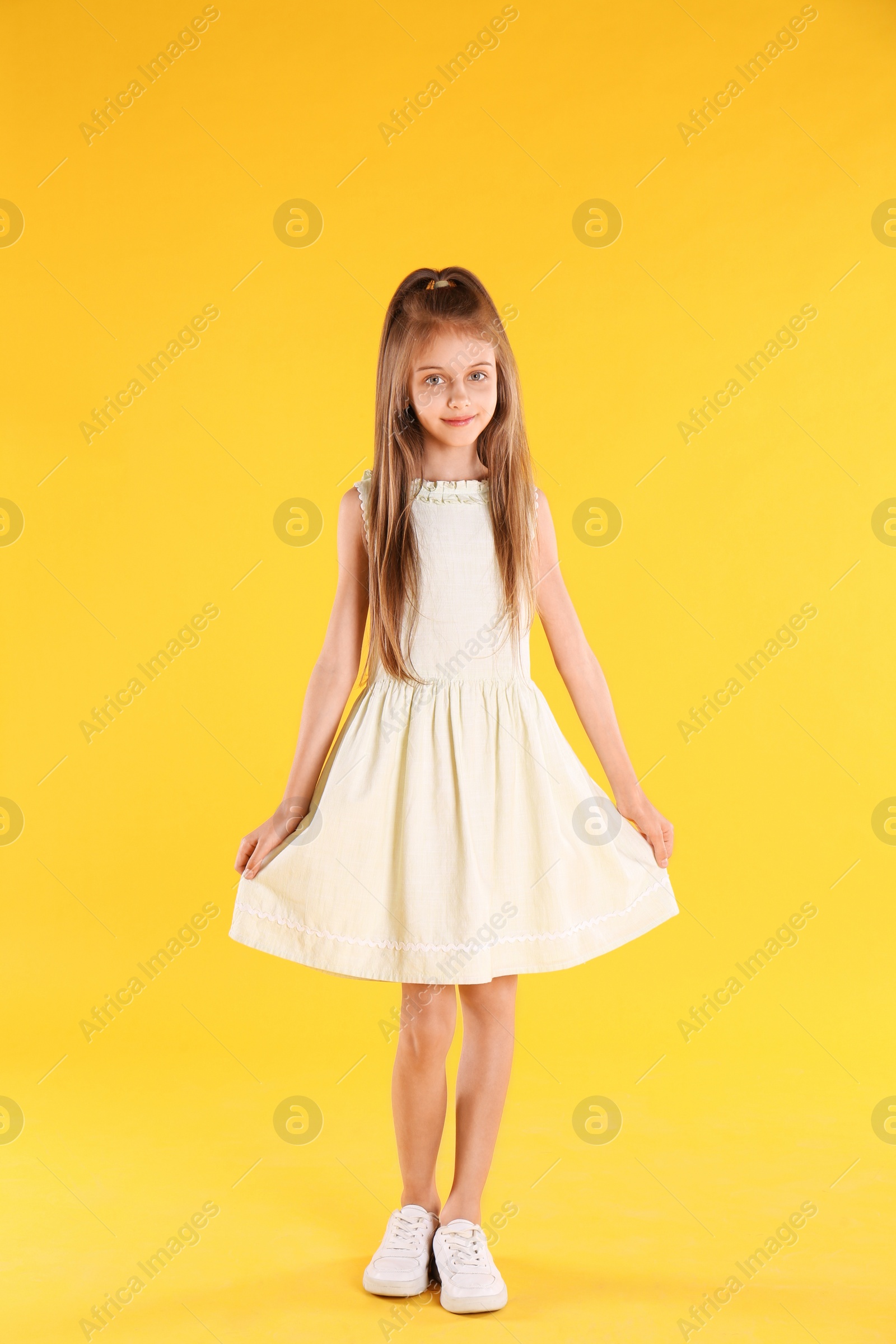 Photo of Full length portrait of cute little girl on yellow background