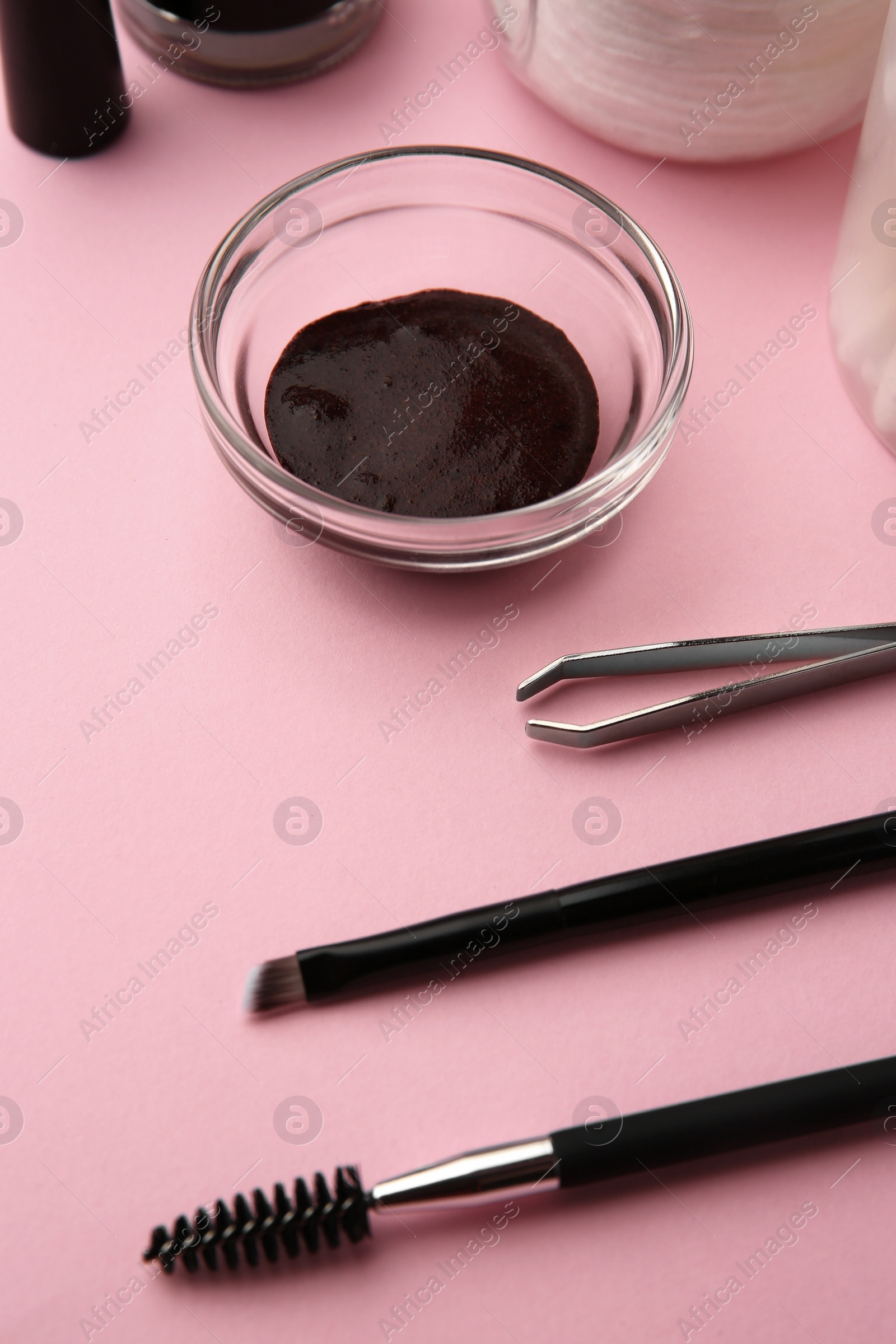 Photo of Eyebrow henna and professional tools on pink background, closeup