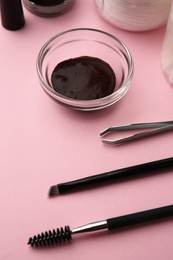 Photo of Eyebrow henna and professional tools on pink background, closeup