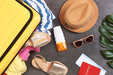 Flat lay composition with suitcase and beach items on gray background