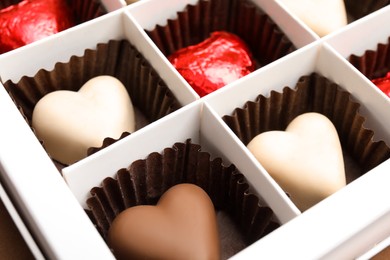 Photo of Tasty heart shaped chocolate candies in box, closeup. Valentine's day celebration