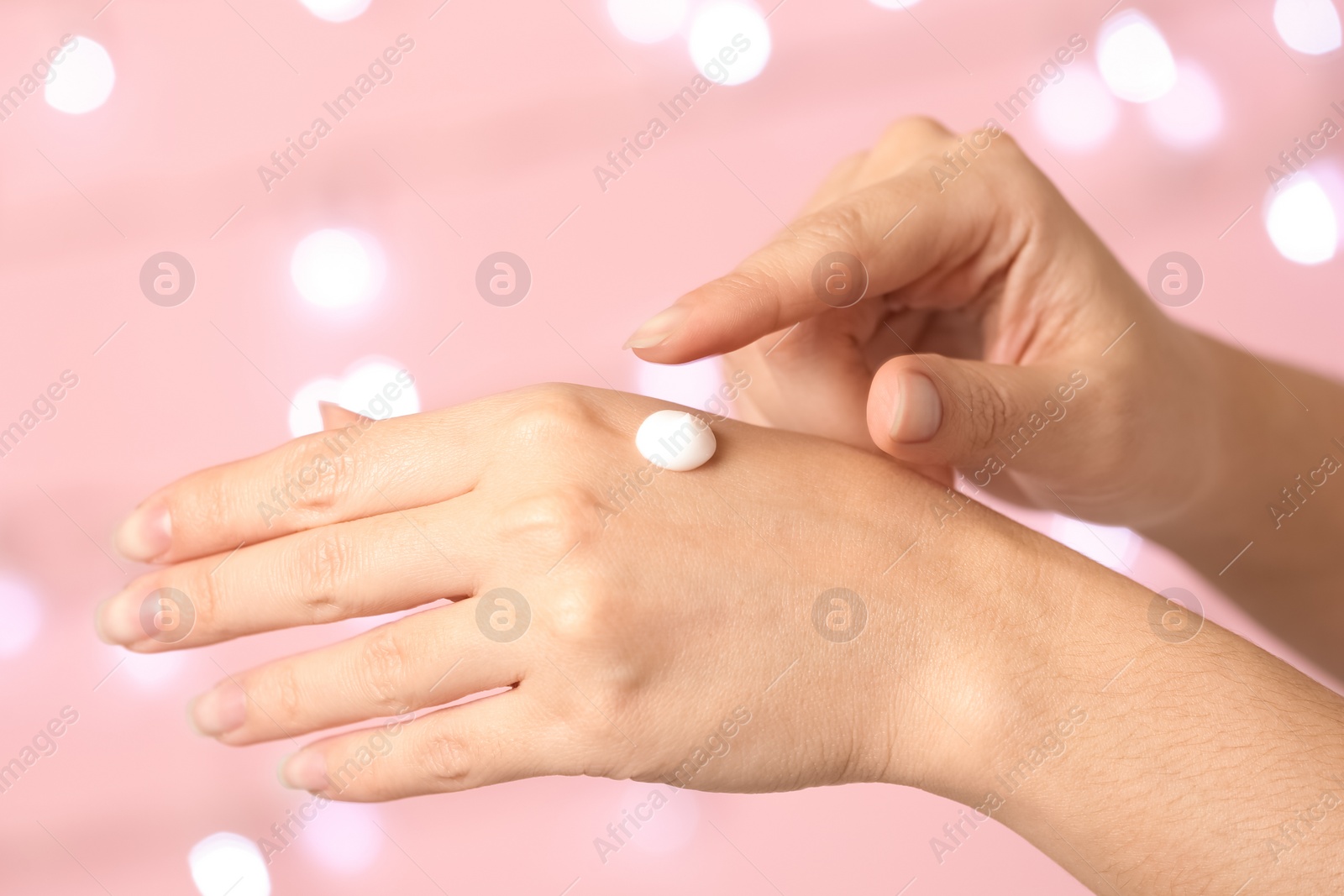 Photo of Woman applying hand cream on blurred background, closeup