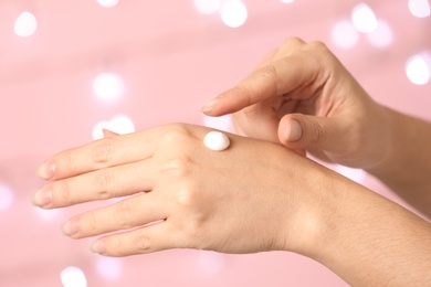 Photo of Woman applying hand cream on blurred background, closeup