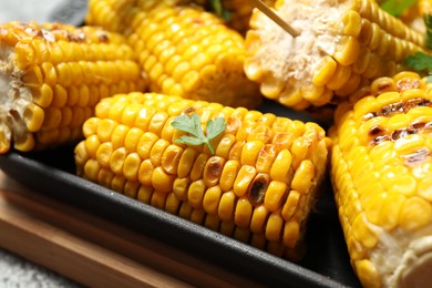 Photo of Tasty grilled corn with parsley, closeup view