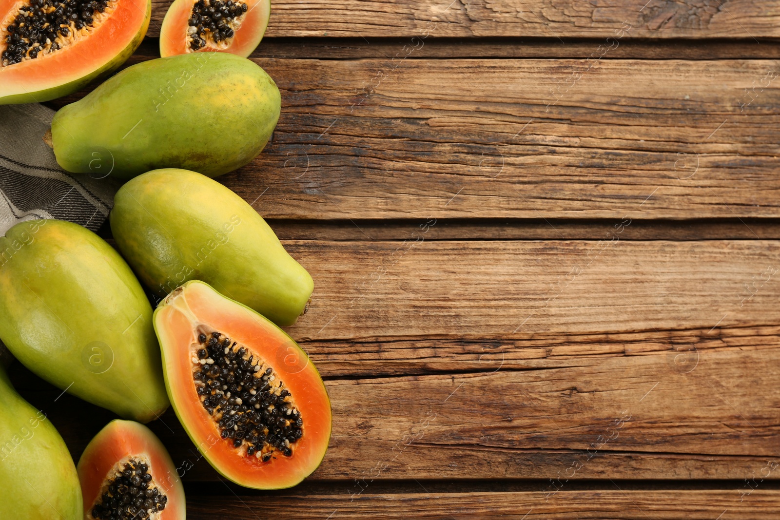 Photo of Fresh ripe papaya fruits on wooden table, flat lay. Space for text