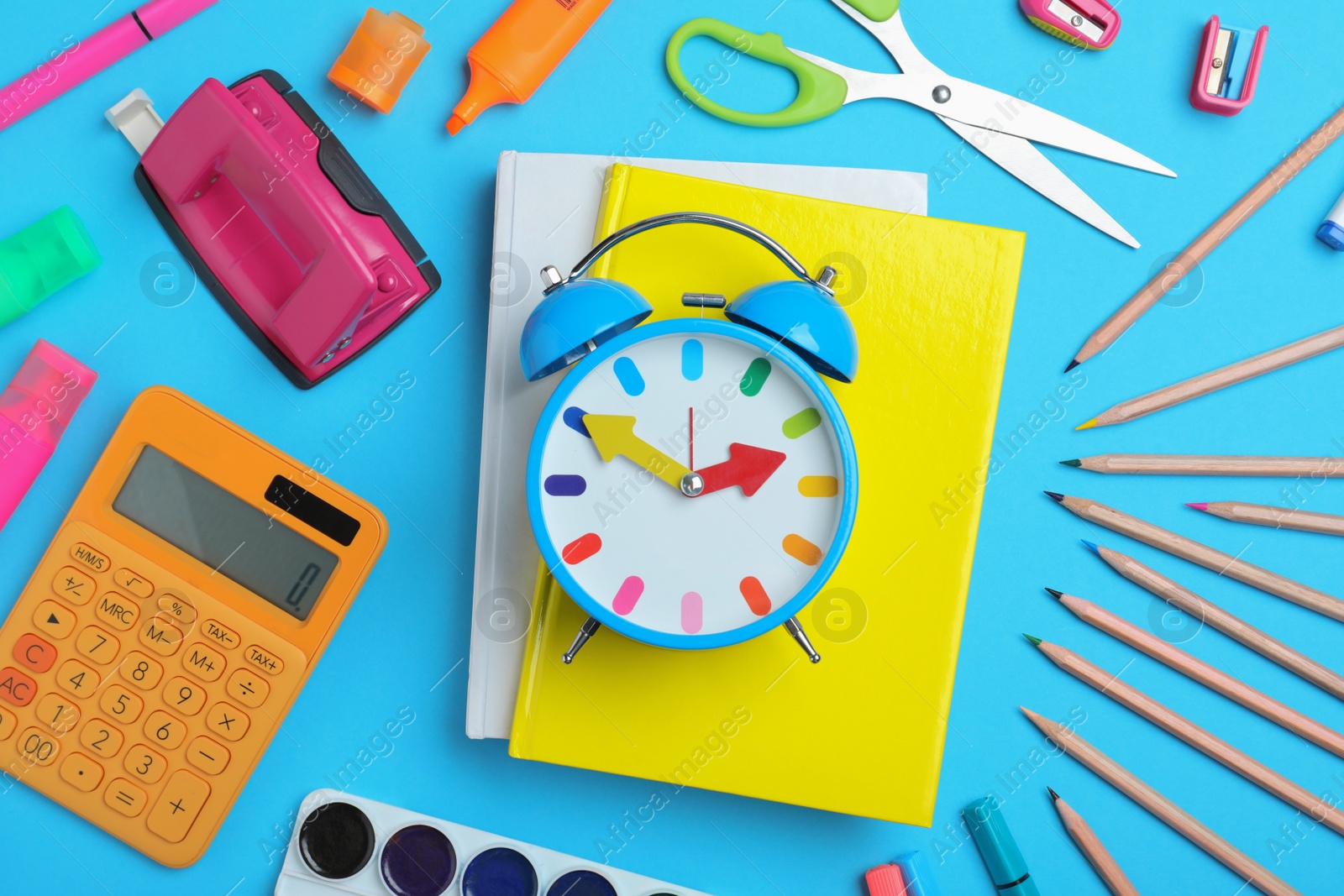 Photo of Flat lay composition with alarm clock and different stationery on light blue background. School time