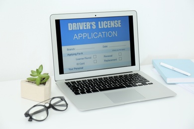 Photo of Laptop with driver's license application form on table in office