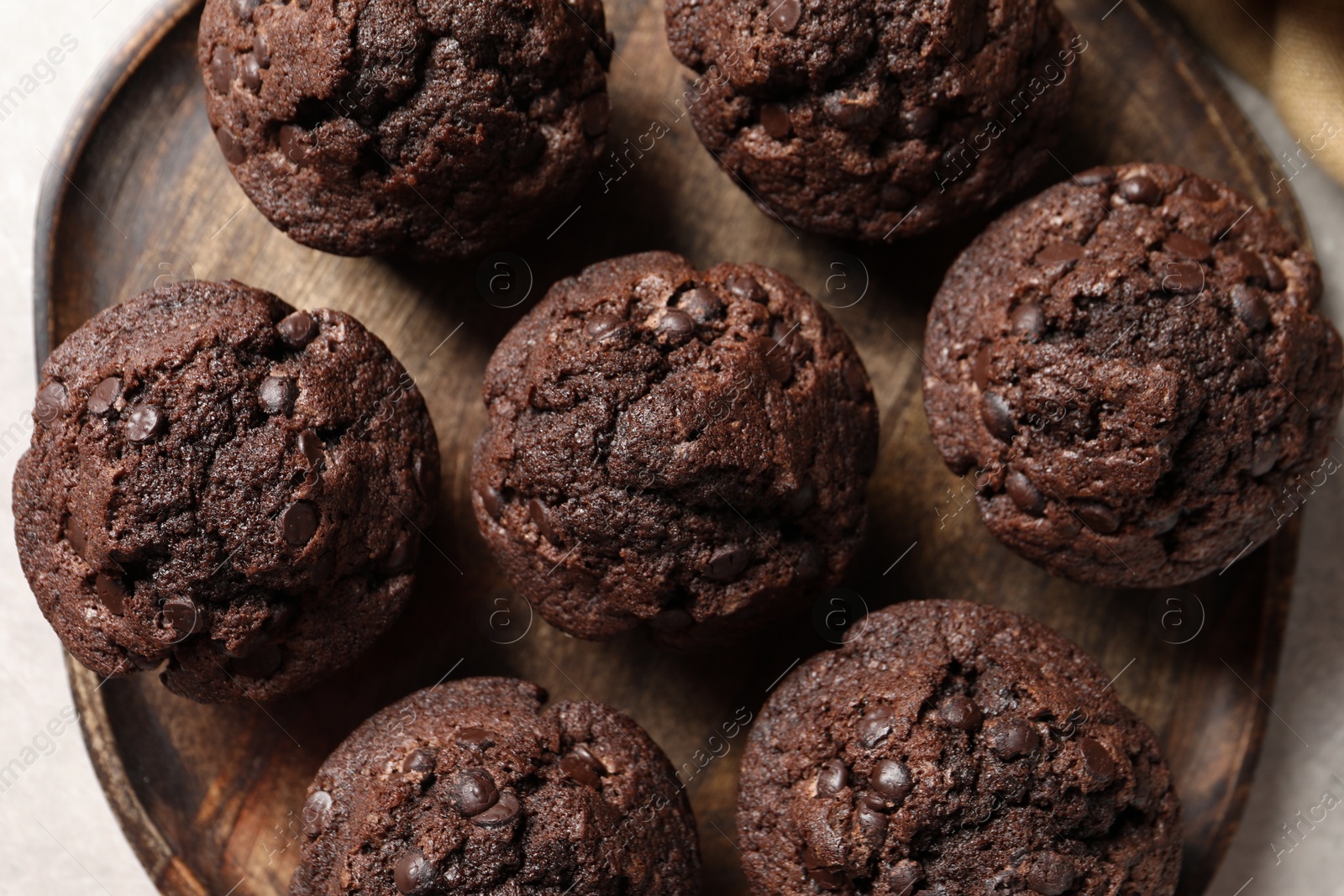 Photo of Board with delicious chocolate muffins on light table, top view