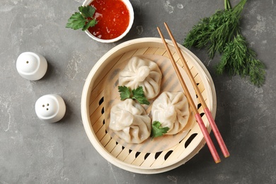 Photo of Bamboo steamer with tasty baozi dumplings and chopsticks on table, top view