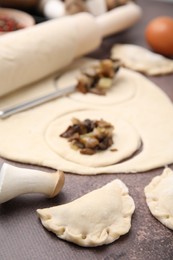 Process of making dumplings (varenyky) with mushrooms. Raw dough and ingredients on grey table, closeup