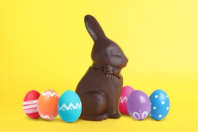 Image of Chocolate bunny and painted Easter eggs on yellow background