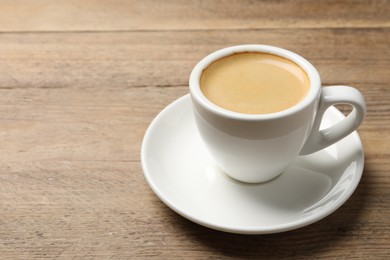 Photo of Aromatic coffee in cup on wooden table. Space for text