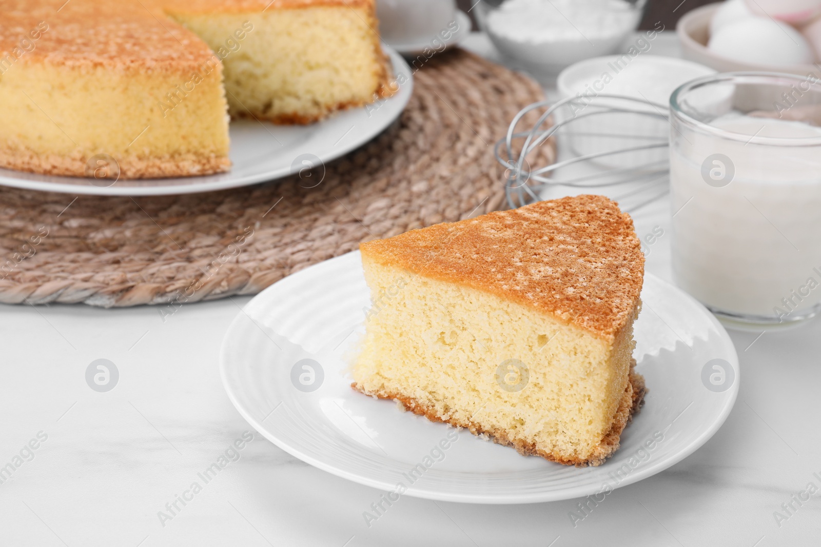 Photo of Plate with piece of tasty sponge cake on white marble table