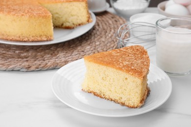 Plate with piece of tasty sponge cake on white marble table