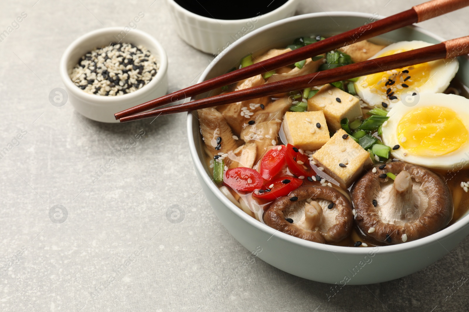 Photo of Delicious ramen served on grey table, closeup. Noodle soup