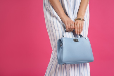 Young woman with stylish blue bag on pink background, closeup. Space for text