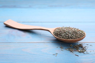 Photo of Spoon with dried thyme on light blue wooden table