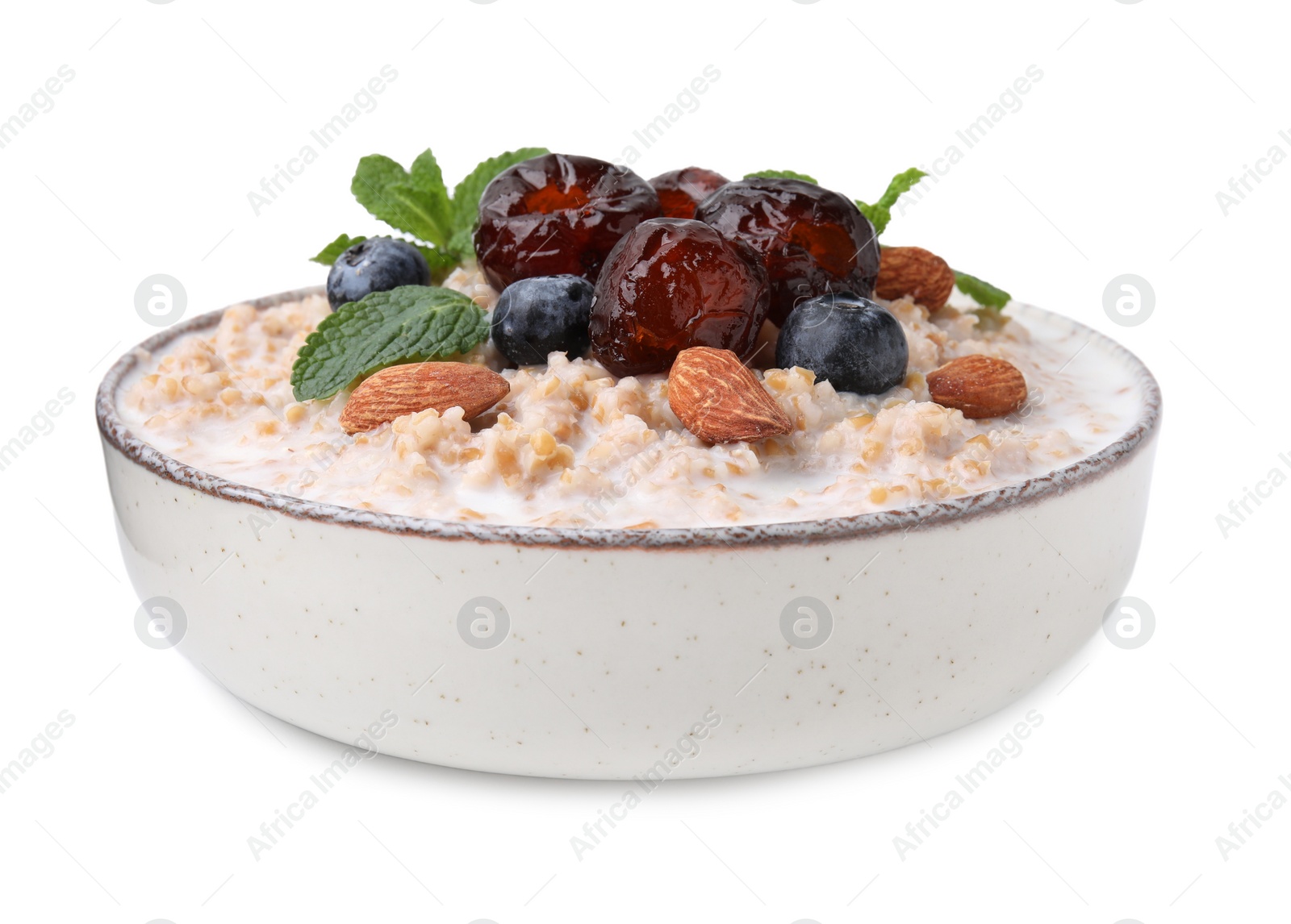 Photo of Tasty wheat porridge with milk, dates, blueberries and almonds in bowl isolated on white