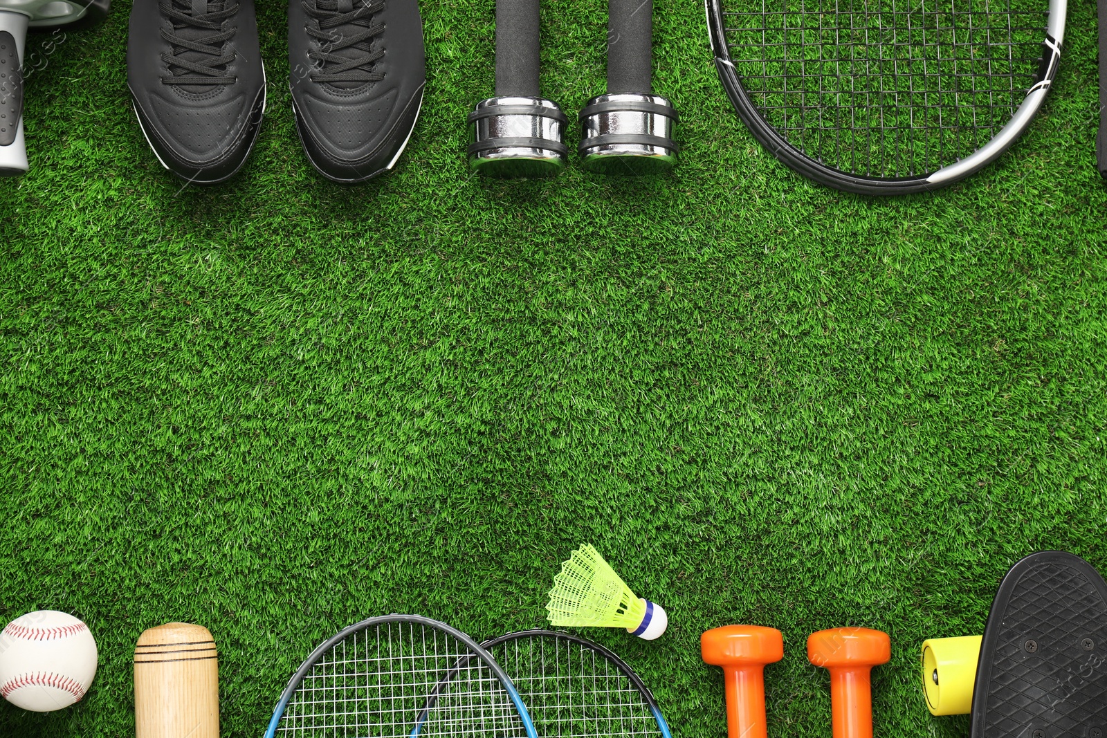 Photo of Different sports equipment on green grass, flat lay. Space for text