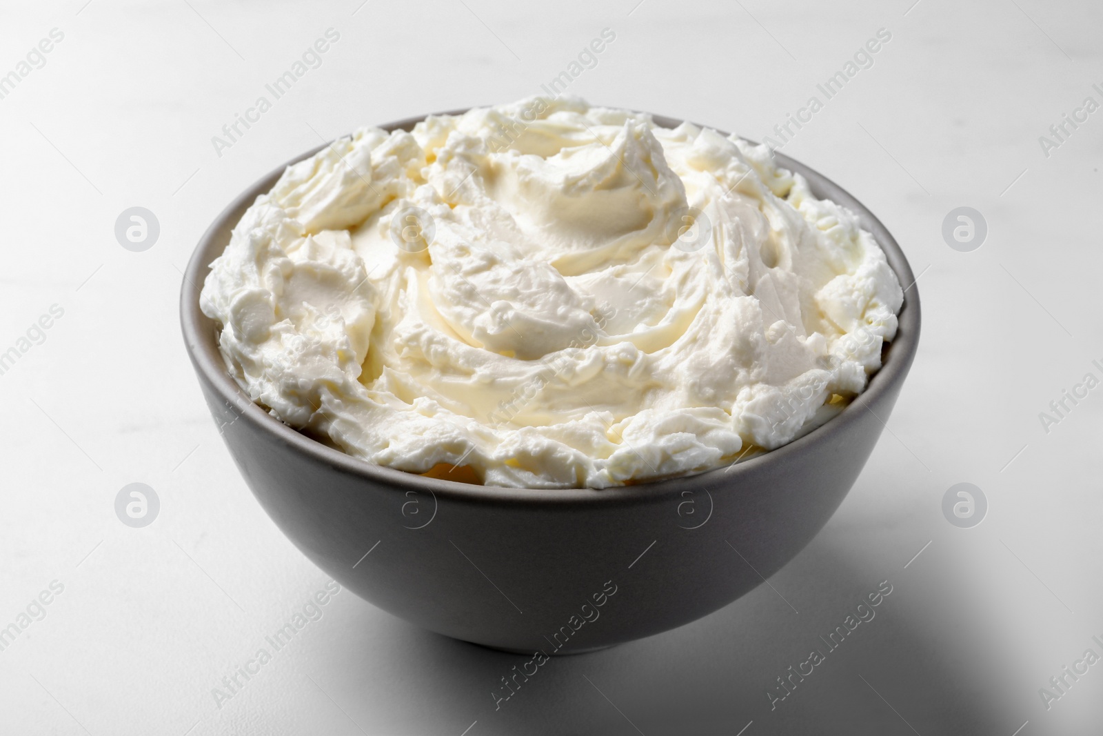 Photo of Bowl of tasty cream cheese on white table