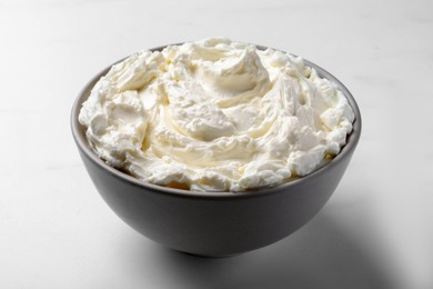 Photo of Bowl of tasty cream cheese on white table