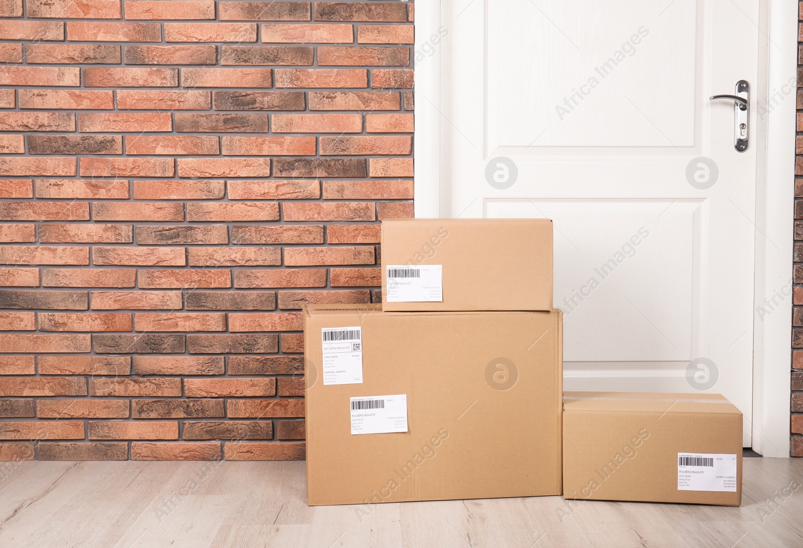 Photo of Cardboard parcel boxes on floor near apartment entrance. Mockup for design