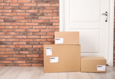 Photo of Cardboard parcel boxes on floor near apartment entrance. Mockup for design