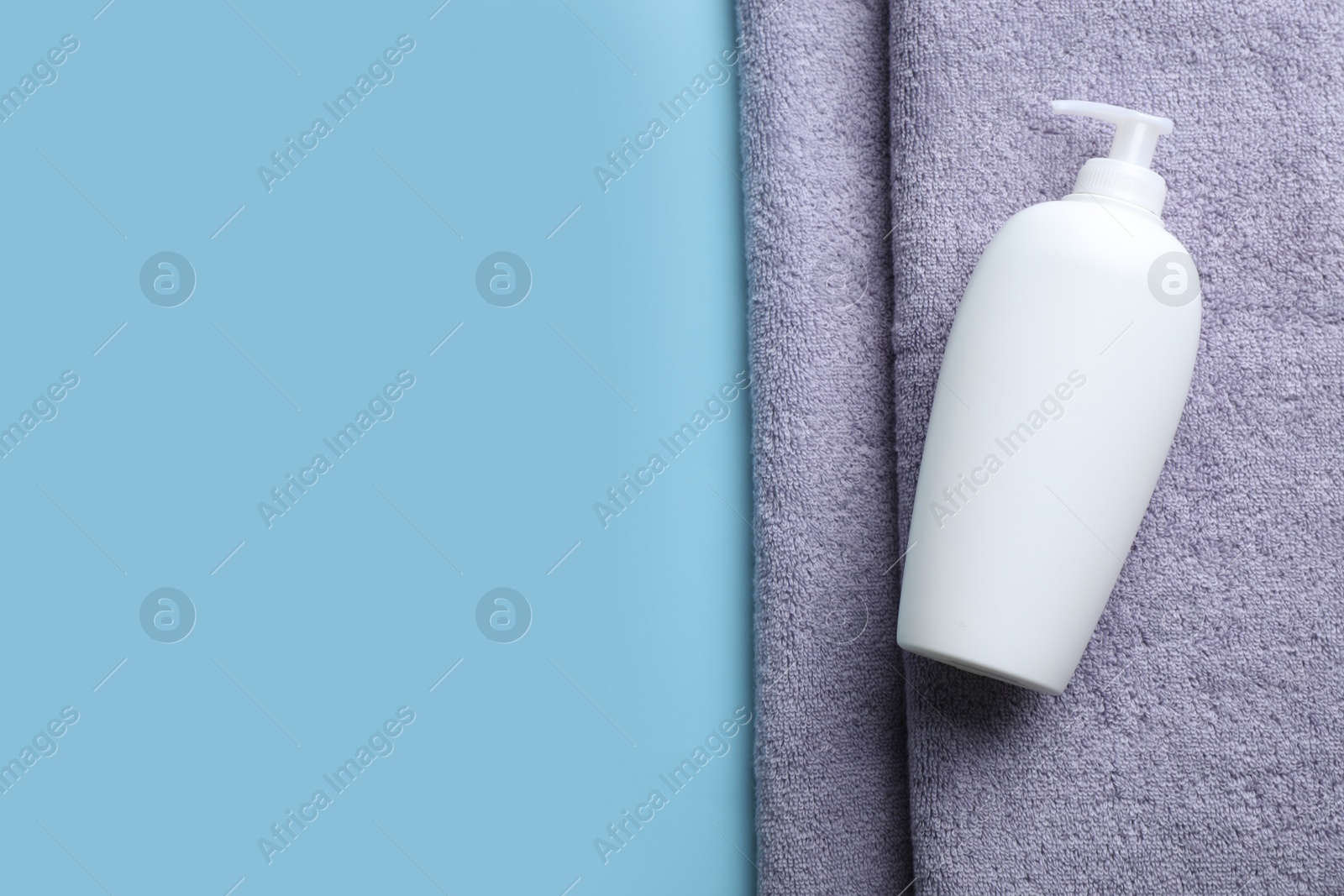 Photo of Bottle of shampoo and towel on color background, top view with space for text