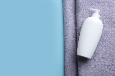 Photo of Bottle of shampoo and towel on color background, top view with space for text