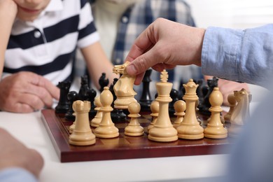 Father and son playing chess indoors, closeup