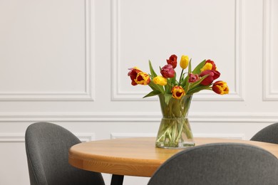 Photo of Vase with beautiful tulips on table in dining room