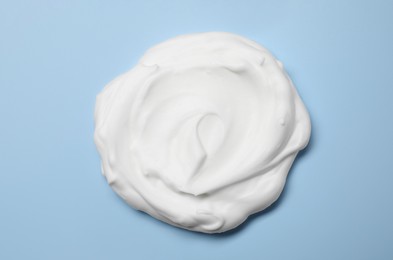 Photo of Sample of shaving foam on light blue background, top view