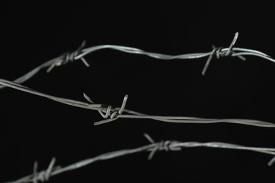Photo of Shiny metal barbed wire on black background, closeup