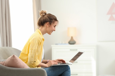 Photo of Young woman using modern laptop at home