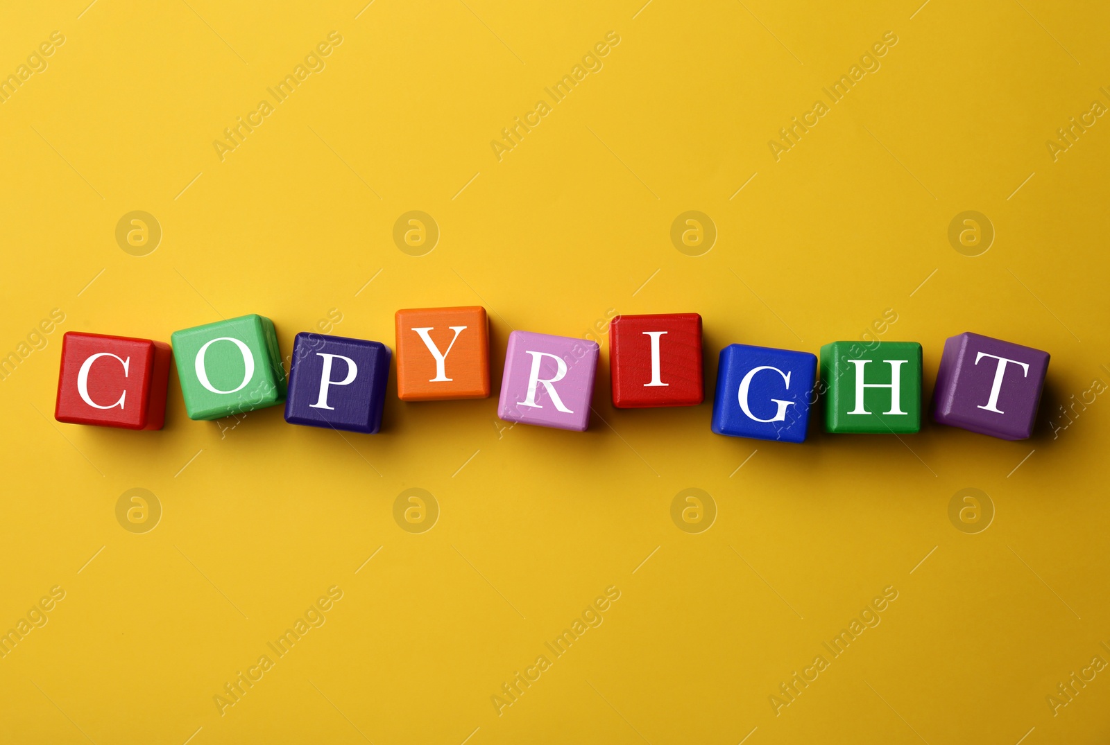 Photo of Plagiarism concept. Word Copyright made of color cubes on yellow background, top view