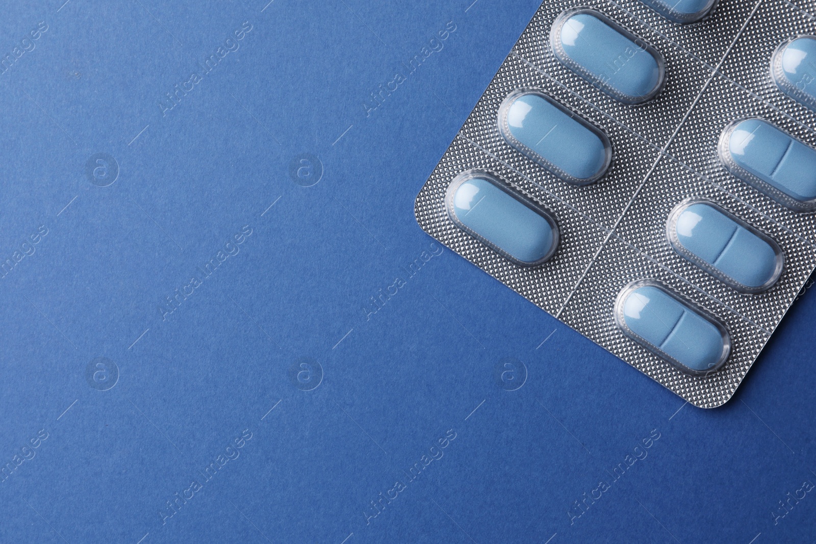 Photo of Pills and space for text on blue background, top view. Potency problem